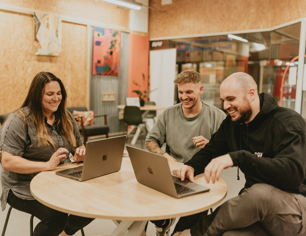 Small editorial team discussing content around a table in a bright office